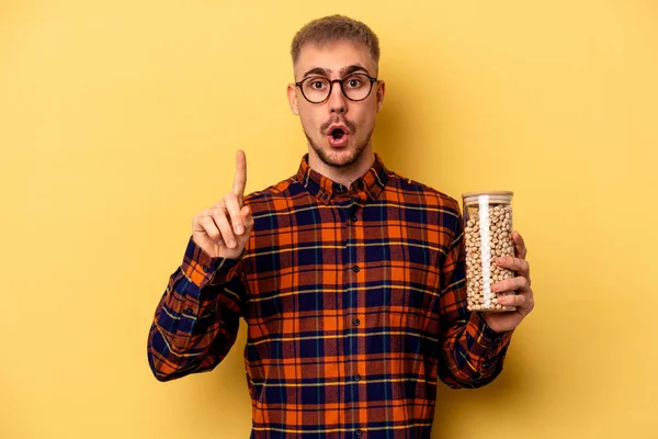 Young Caucasian Man Holding Chickpeas Isolated Yellow Background Having Some — Stock fotografie