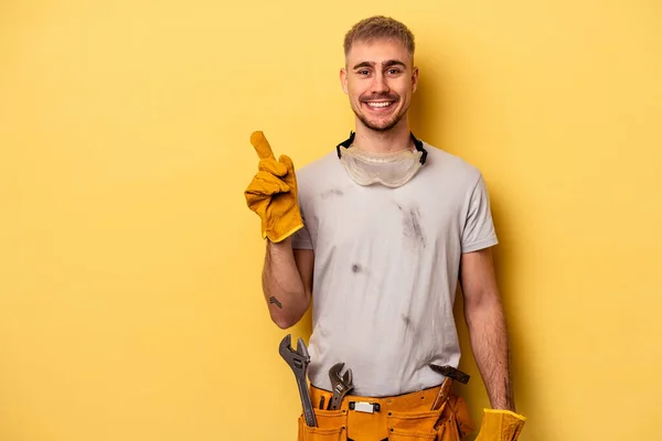 Jovem Eletricista Caucasiano Isolado Fundo Amarelo Sorrindo Apontando Para Lado — Fotografia de Stock