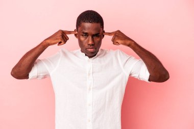 Pembe arka planda izole edilmiş genç Afrikalı Amerikalı bir adam bir göreve odaklanmış, işaret parmaklarını işaret ediyor..