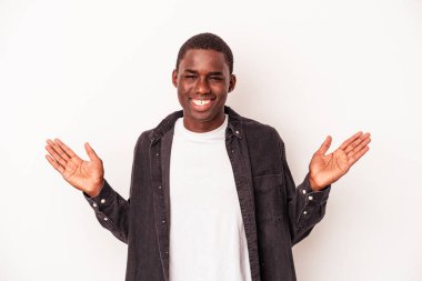 Beyaz arka planda izole edilmiş genç Afrikalı Amerikalı adam kollarıyla ölçek oluşturuyor, mutlu ve kendinden emin hissediyor..