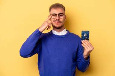 Young computer man isolated on yellow background showing a disappointment gesture with forefinger.