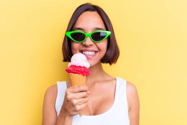 Sarı arka planda izole edilmiş dondurma tutan melez bir kadın.