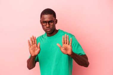 Genç Afro-Amerikalı, pembe arka planda izole edilmiş, elini uzatmış, dur işareti göstererek, seni engelliyor..