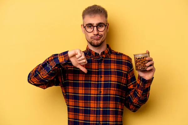 Young Caucasian Man Holding Almond Jar Isolated Yellow Background Showing — Stockfoto