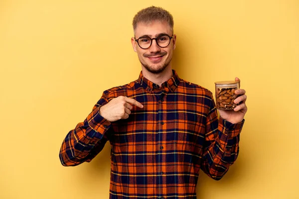 Young Caucasian Man Holding Almond Jar Isolated Yellow Background Person — Zdjęcie stockowe