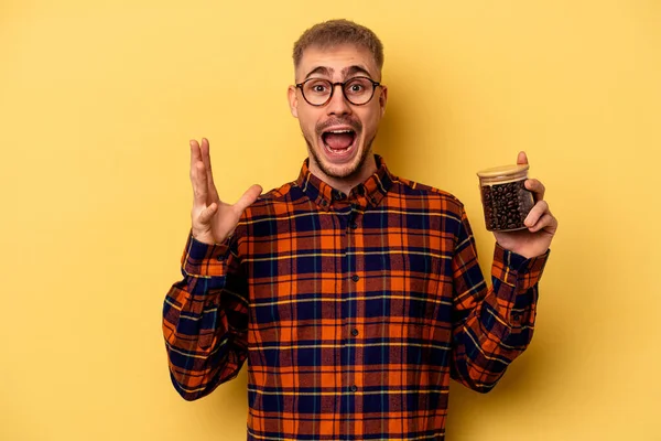 Young Caucasian Man Holding Coffee Jar Isolated Yellow Background Receiving — Stock fotografie