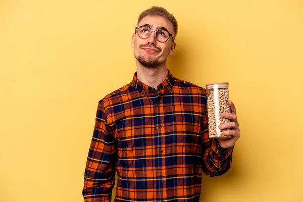 Young Caucasian Man Holding Chickpeas Isolated Yellow Background Dreaming Achieving — Stockfoto