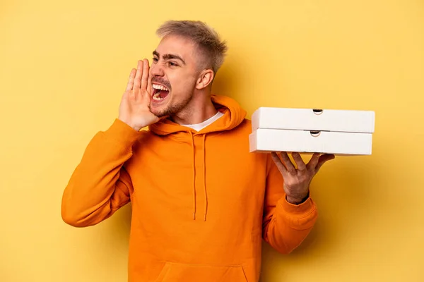 Young Caucasian Man Holding Pizzas Isolated Yellow Background Shouting Holding — 스톡 사진