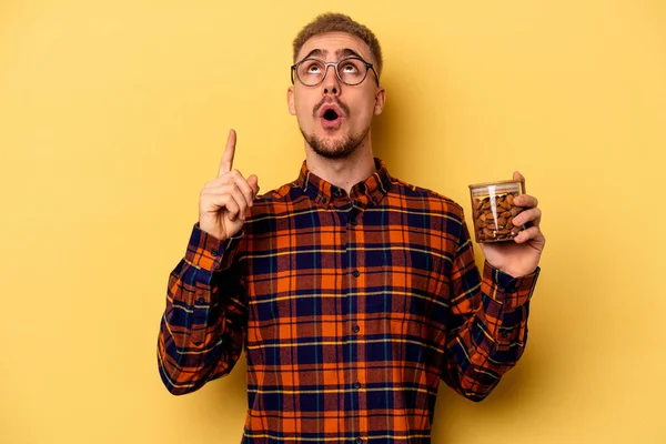 Young Caucasian Man Holding Almond Jar Isolated Yellow Background Pointing — Stock fotografie