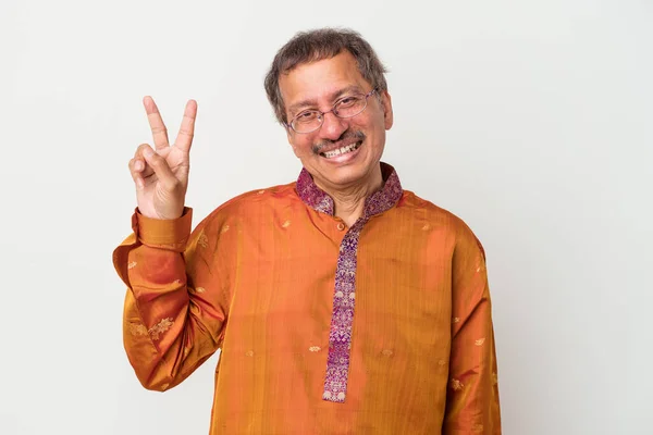 Senior indian man wearing a Indian costume isolated on white background joyful and carefree showing a peace symbol with fingers.
