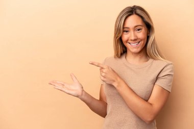 Beyaz tenli genç bir kadın, bej arka planda izole edilmiş. Elinde bir fotokopi odası olduğu için heyecanlı..