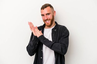 Beyaz arka planda izole olmuş genç beyaz bir adam enerjik ve rahat hissediyor, ellerini ovuşturuyor..