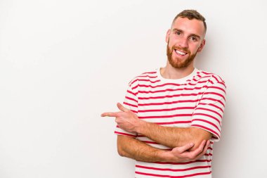 Beyaz arka planda izole edilmiş genç beyaz adam işaret parmağıyla işaret ederek gülümsüyor..