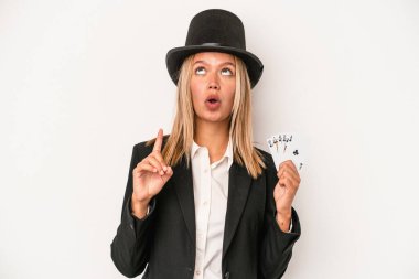 Young caucasian wizard woman holding magic card isolated on white background pointing upside with opened mouth.