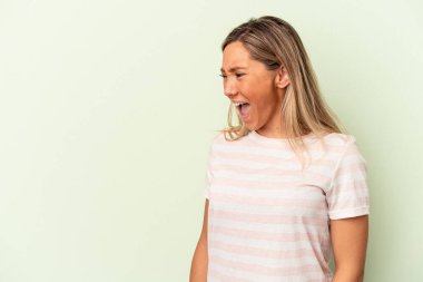 Yeşil arka planda izole edilmiş genç beyaz kadın çok kızgın, öfkeli, hayal kırıklığına uğramış.