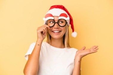 Sarı arka planda izole edilmiş bir Noel aksesuarı tutan beyaz bir kadın.