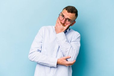 Kafkasyalı genç adam mavi arka planda izole edilmiş korkmuş ve korkmuş..