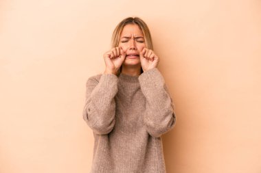 Beyaz tenli genç bir kadın bej arka planda izole edilmiş sızlanıyor ve ağlıyordu..