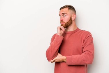 Beyaz arka planda izole edilmiş genç beyaz bir adam rahatlamış bir şeyin fotokopi odasına baktığını düşünüyor..