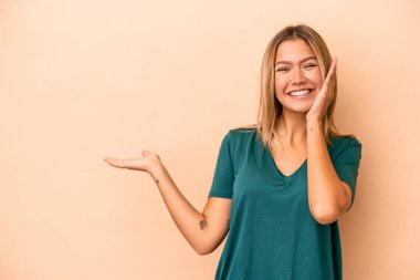 Bej arka planda izole edilmiş beyaz bir kadın avuç içinde fotokopi alanı tutuyor, el üstünde tutuyor. Şaşırmış ve mutlu..