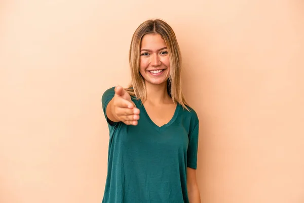 Young Caucasian Woman Isolated Beige Background Stretching Hand Camera Greeting — Stock Photo, Image