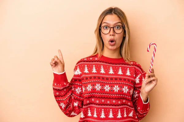 Young Caucasian Woman Holding Christmas Stick Isolated Beige Background Pointing — ストック写真