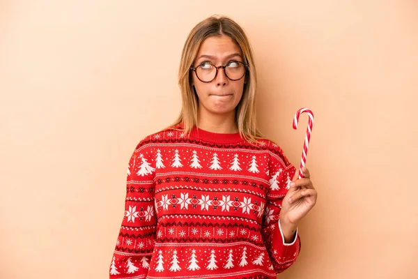 Young Caucasian Woman Holding Christmas Stick Isolated Beige Background Confused — Stok fotoğraf