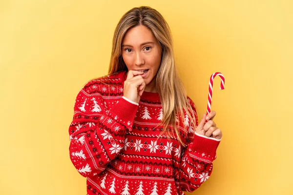 Young Caucasian Woman Holding Christmas Stick Isolated Yellow Background Biting — Stock Photo, Image