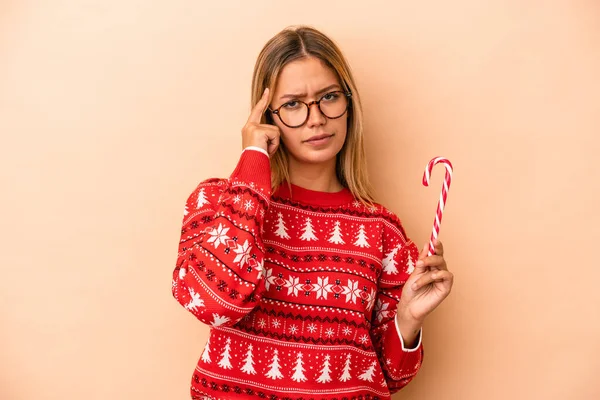 Young Caucasian Woman Holding Christmas Stick Isolated Beige Background Pointing — Stok fotoğraf