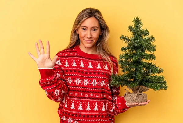 Junge Kaukasische Frau Hält Einen Kleinen Weihnachtsbaum Auf Gelbem Hintergrund — Stockfoto