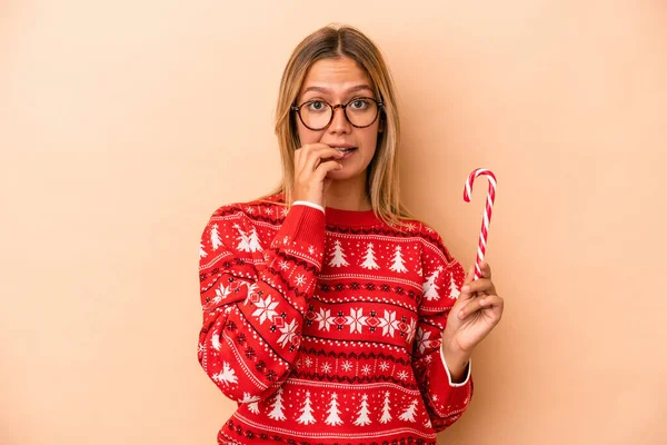 Young Caucasian Woman Holding Christmas Stick Isolated Beige Background Biting — Stock fotografie