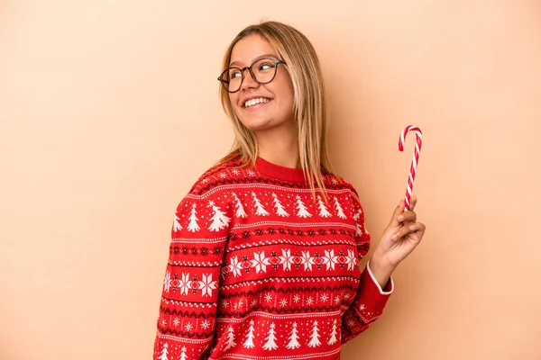 Young Caucasian Woman Holding Christmas Stick Isolated Beige Background Looks — Stok fotoğraf