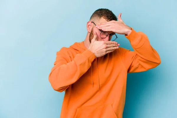 Ung Kaukasisk Man Isolerad Blå Bakgrund Blinka Vid Kameran Genom — Stockfoto