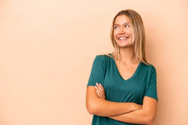 Bej arka planda izole edilmiş beyaz bir kadın. Kollarını kavuşturup gülümsüyor..