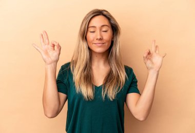 Beyaz tenli genç bir kadın, bej arka planda izole edilmiş yoğun çalışma gününden sonra rahatlıyor, yoga yapıyor..