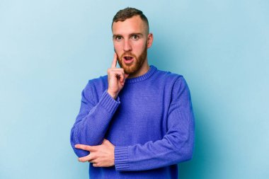 Kafkasyalı genç adam mavi arka planda izole edildi. Harika bir fikri var, yaratıcılık kavramı..