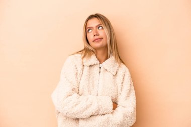 Beyazlı genç bir kadın bej arka planda izole edilmiş hedeflerine ve amaçlarına ulaşma hayali kuruyor.