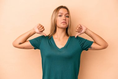 Bej arka planda izole edilmiş genç beyaz kadın gururlu ve kendinden emin hissediyor, örnek olarak.