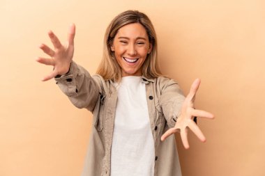 Beyazlı genç bir kadın bej arka planda izole edilmiş kameraya sarılıyor..