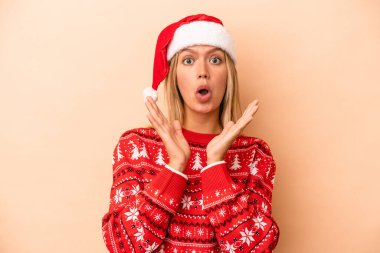 Young caucasian woman celebrating Christmas isolated on beige background surprised and shocked.
