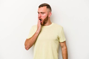 Beyaz arka planda izole edilmiş genç beyaz adam esniyor. Ağzı eliyle kapatan yorgun bir hareket sergiliyor..
