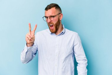 Mavi arka planda izole edilmiş genç beyaz adam iki numarayı parmaklarıyla gösteriyor..