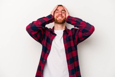 Beyaz arka planda izole olmuş genç beyaz bir adam ellerini başının üstünde tutarak neşeyle gülüyor. Mutluluk kavramı.