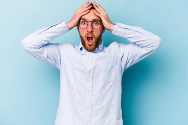 Kafkasyalı genç adam mavi arka planda izole edildi. Şaşırdı ve şok oldu..