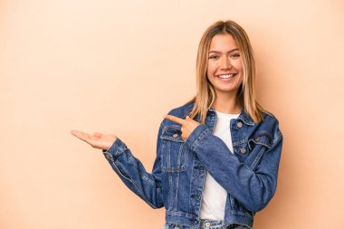 Beyaz tenli genç bir kadın, bej arka planda izole edilmiş. Elinde bir fotokopi odası olduğu için heyecanlı..