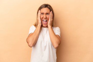 Beyazlı genç bir kadın bej arka planda izole edilmiş kulakları kulaklarıyla kapatıyor çok fazla ses duymamaya çalışıyor..
