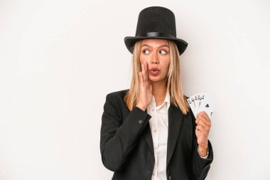Young caucasian wizard woman holding magic card isolated on white background is saying a secret hot braking news and looking aside