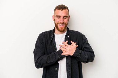 Beyaz arka planda izole edilmiş beyaz tenli genç bir adam, dostane bir ifadeye sahip, avuçlarını göğsüne bastırıyor. Aşk konsepti.