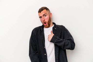 Beyaz arka planda izole edilmiş genç beyaz bir adam parmağını göstererek şaşırdı, geniş bir gülümsemeyle..