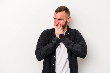 Beyaz arka planda izole olmuş genç beyaz bir adam bir şeye gülüyor, ağızlarını ellerle kapatıyor..